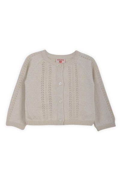Short, beige knitted baby cardigan with lace and pom-poms. 